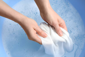 A bowl of white laundry soaking in baking soda water as part of a natural whitening tip.